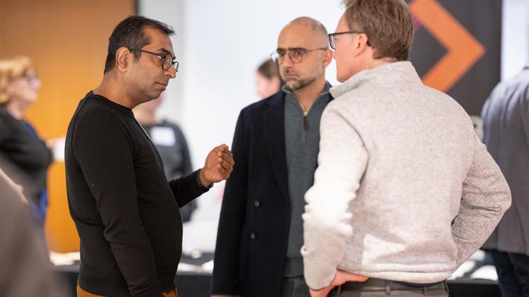 three men stand together talking